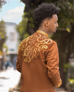 Person wearing a brown jacket with gold embroidery outdoorsBrown Habesha Men’s Shirt with Golden Design | Modern Ethiopian Wear ethgebya
