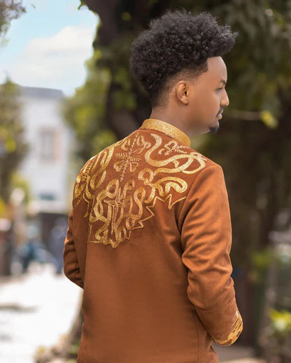 Person wearing a brown jacket with gold embroidery outdoorsBrown Habesha Men’s Shirt with Golden Design | Modern Ethiopian Wear ethgebya