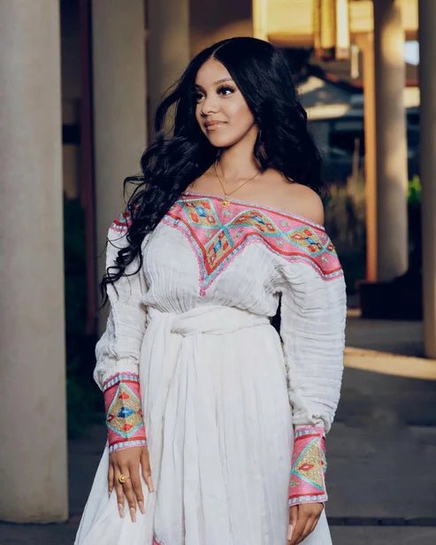 Woman wearing a white dress with colorful embroidery outdoors