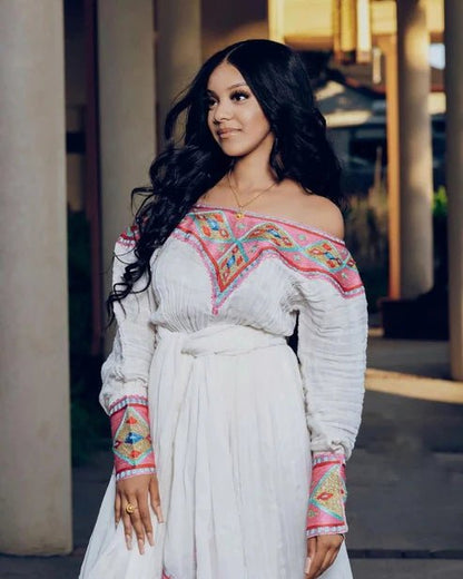 Woman wearing a white dress with colorful embroidery outdoors