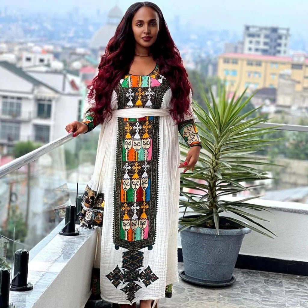 Woman in a colorful dress standing on a balcony with a cityscape background