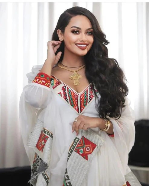 Woman wearing a white embroidered traditional outfit with colorful patterns.