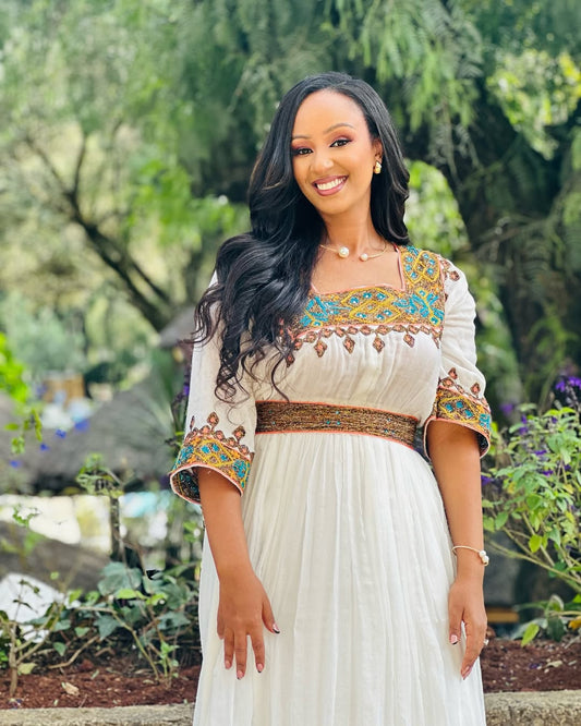Woman in a traditional outfit standing outdoors with greenery in the background Light Green & Gold Zuria Habesha Kemis Ethgebya