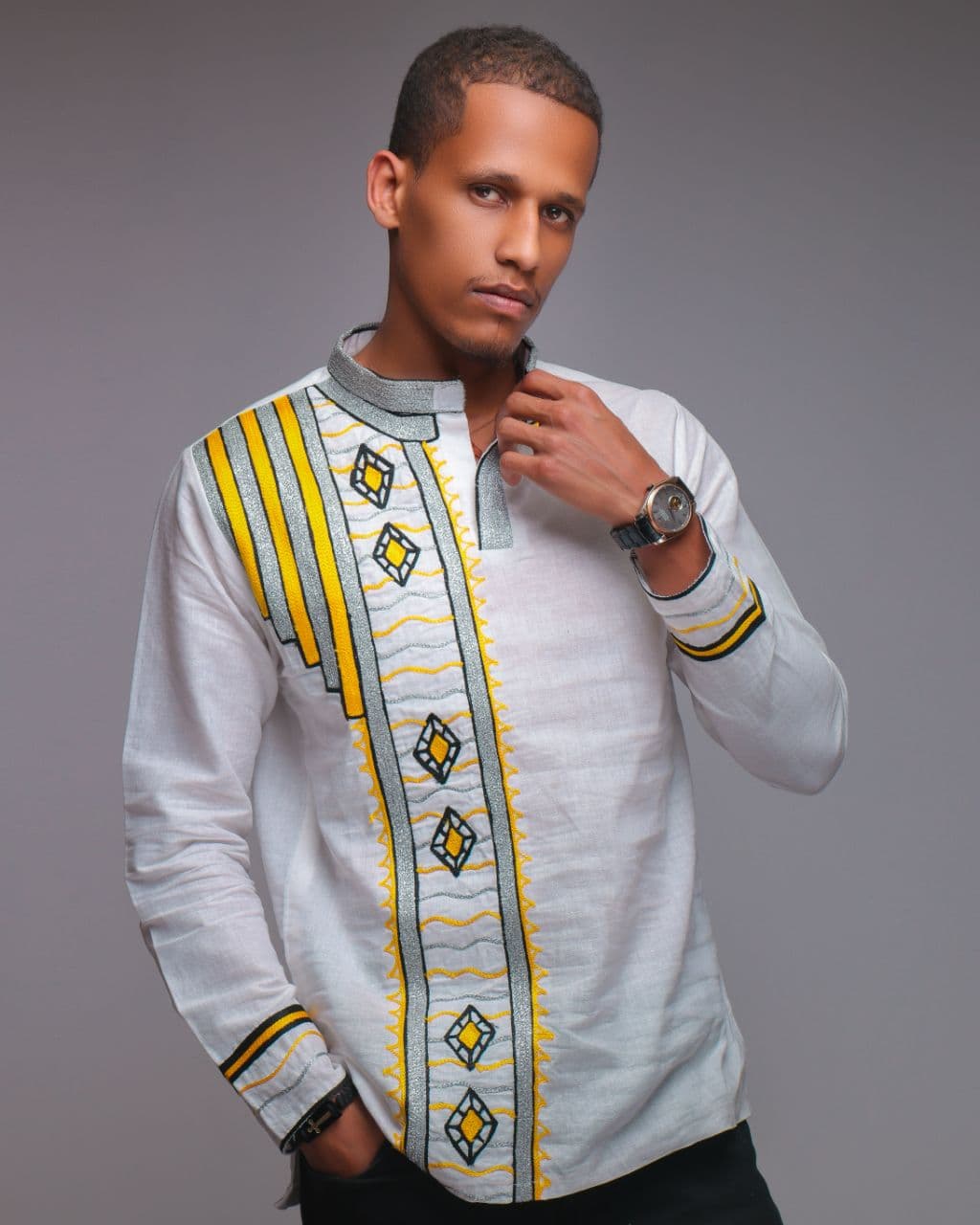 Man wearing a patterned shirt with yellow and gray design on a gray background
